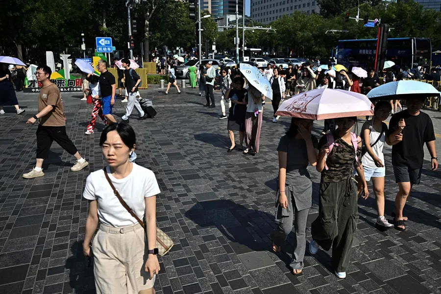 People walk on an esplanade in Beijing on 3 August 2025. (Pedro Pardo/AFP)