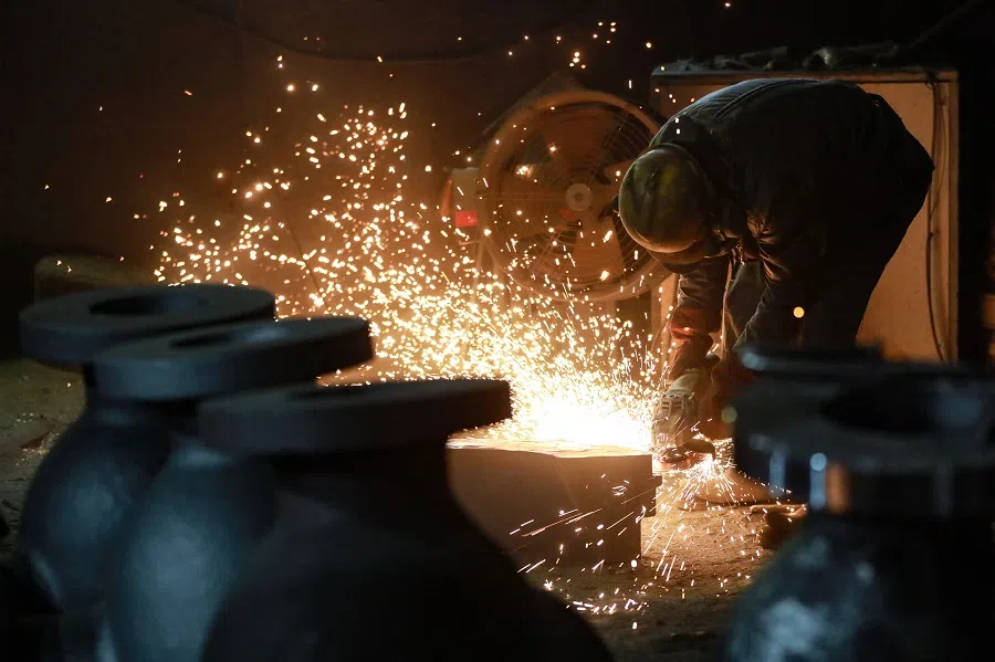 A worker polishes machinery in the workshop of a factory which produces steel machinery for export, in Hangzhou, Zhejiang province, China, on 21 February 2025. (AFP)