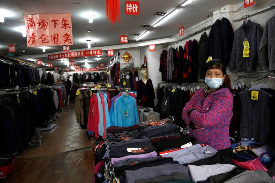 A staff wearing a face mask waits for customers inside a clothing store where business has been struggling since the Covid-19 outbreak, in Beijing, China, on 14 April 2020. (Tingshu Wang/Reuters)