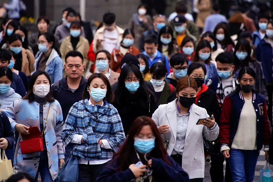 People wearing face masks walk on a street in Shanghai, China, 30 March 2021. (Aly Song/Reuters)