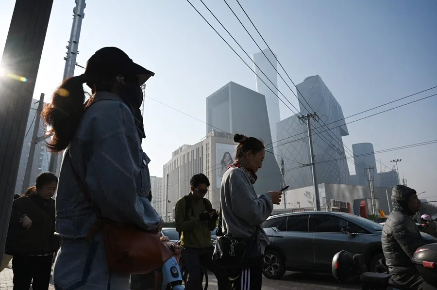 People wait to cross a road on their way to work in Beijing’s central business district on 10 April 2025. (Greg Baker/AFP)