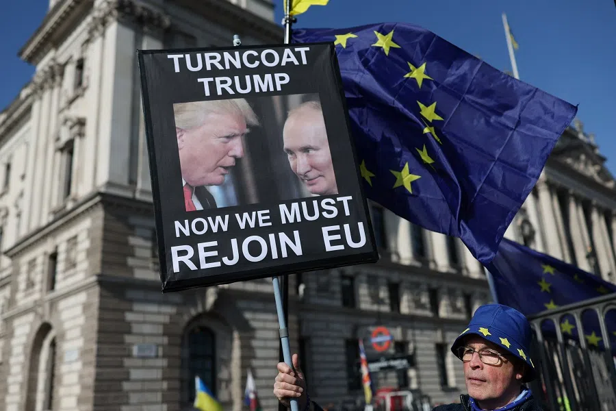 An anti-Brexit demonstrator stands with a placard depicting US President Donald Trump and Russian President Vladimir Putin next to European Union flags during a protest outside the Houses of Parliament in Westminster, London, Britain, on 5 March 2025. (Isabel Infantes/Reuters)