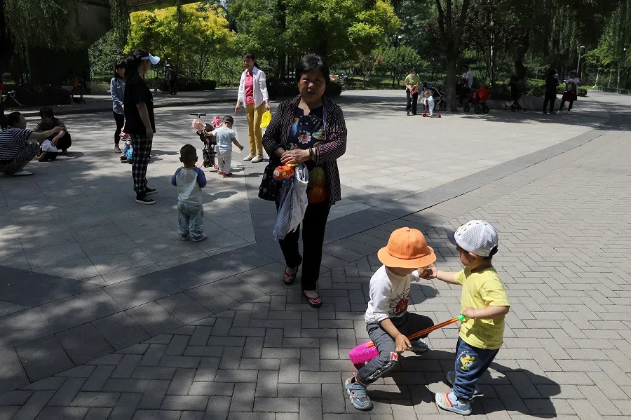 Children play next to adults at a park in Beijing, China, 1 June 2021. (Tingshu Wang/File Photo/Reuters)