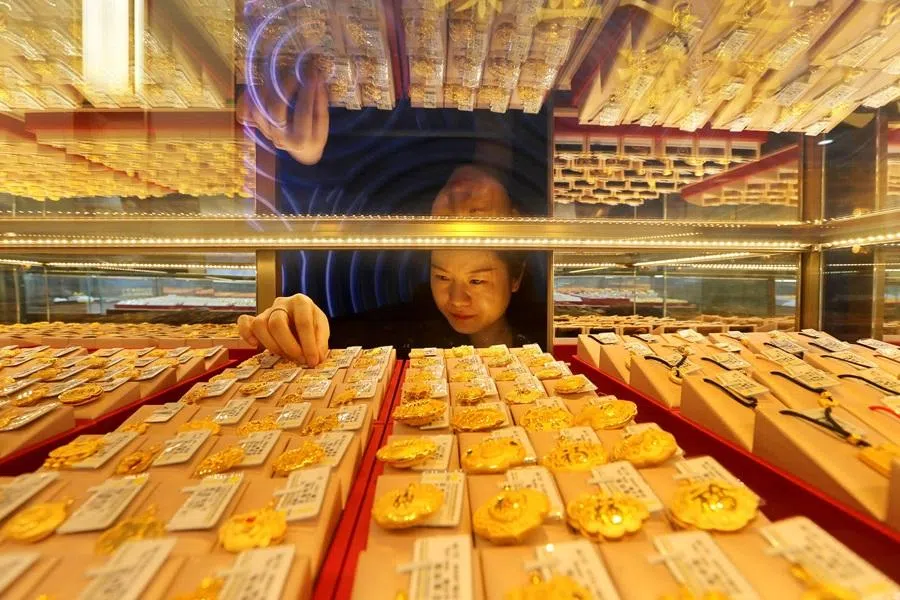 A saleswoman adjusts gold jewellery for sale at a shop in Lianyungang, Jiangsu province, on 24 December 2025.