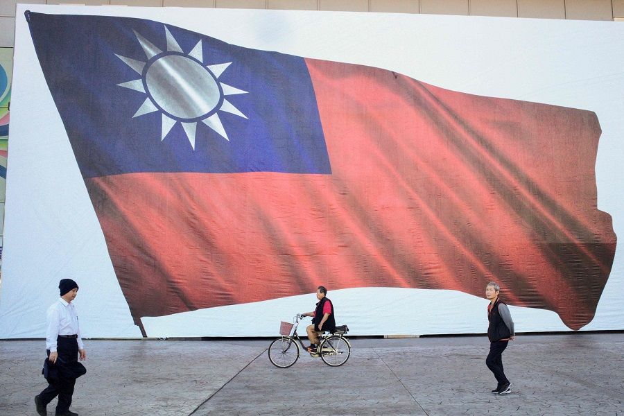 People walk past a Taiwanese flag in New Taipei City on 13 January 2024. (Sam Yeh/AFP)