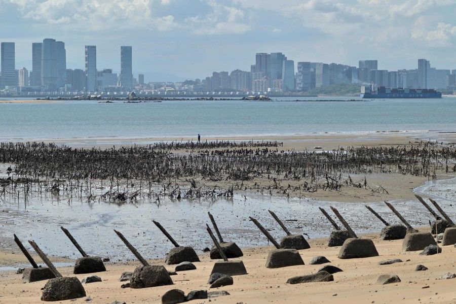 The Xiamen city skyline on the Chinese mainland is seen past anti-landing spikes placed along the coast of Lieyu islet on Taiwan's Kinmen islands, which lie just 3.2 km (two miles) from the mainland China coast, on 10 August 2022. (Sam Yeh/AFP)