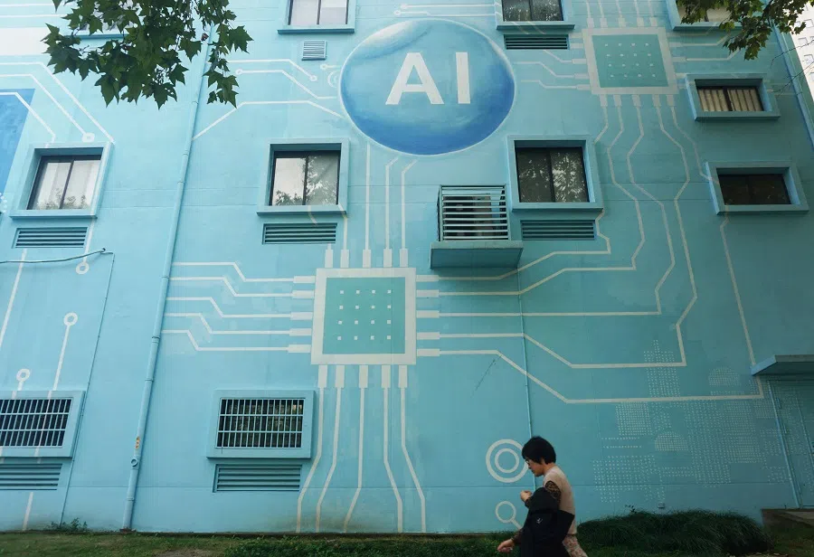 A woman walks past a building whose exterior wall was painted to look like a circuit board with an AI logo in Hangzhou, Zhejiang province, China, on 30 October 2024.