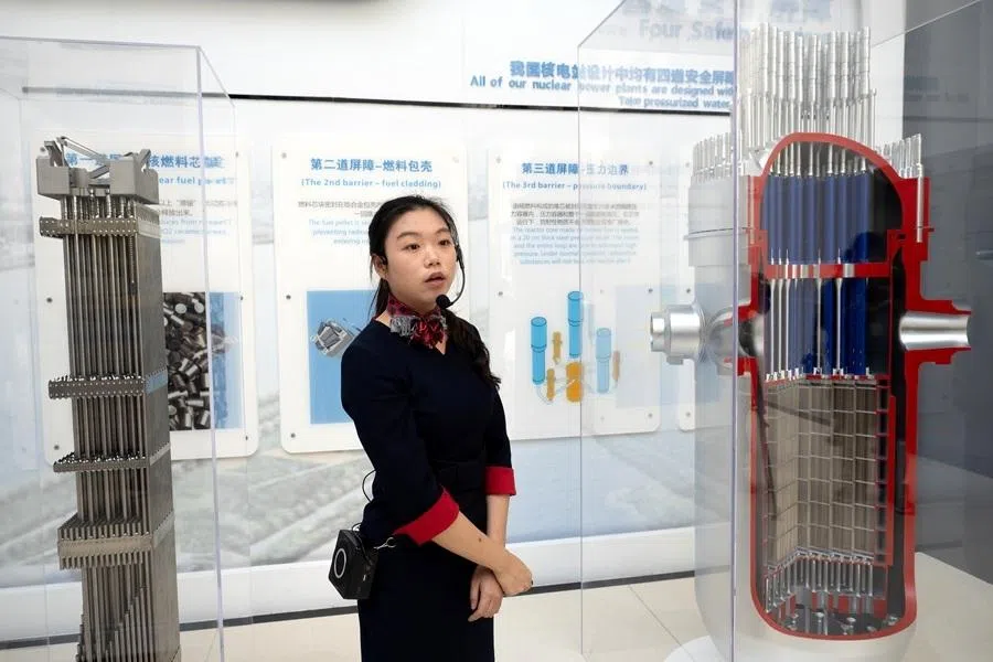 A staff giving a tour of Hualong One technology, next to models of the interior of the nuclear reactor to show its safety features.