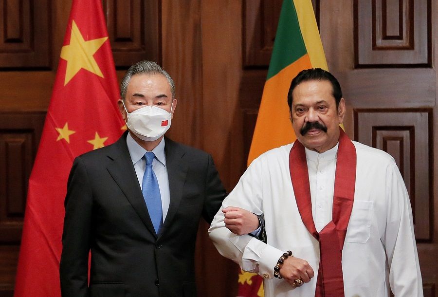 Chinese Foreign Minister Wang Yi (left) poses for a photograph with Sri Lanka's Prime Minister Mahinda Rajapaksa during their bilateral meeting in Colombo, Sri Lanka, 9 January 2022. (Dinuka Liyanawatte/Reuters)