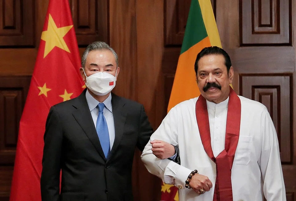 Chinese Foreign Minister Wang Yi (left) poses for a photograph with Sri Lanka's Prime Minister Mahinda Rajapaksa during their bilateral meeting in Colombo, Sri Lanka, 9 January 2022. (Dinuka Liyanawatte/Reuters)