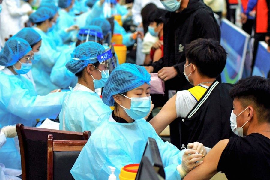 This photo taken on 30 March 2021 shows a medical staff member (centre) administering a dose of the Sinovac Covid-19 coronavirus vaccine at a university in Qingdao in China's eastern Shandong province. (STR/AFP)
