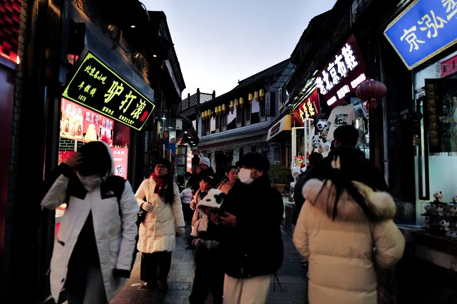 People walk in a commercial street at the historical Shichahai district in Beijing, China, 3 December 2025. (Sarah Meyssonnier/Reuters)