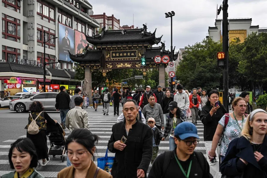 People cross a street next to Yu Garden in the Huangpu district in Shanghai, on 21 October 2025. (Hector Retamal/AFP)