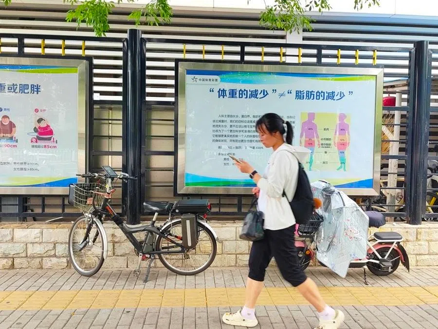 A woman walks past a display promoting weight management in China.