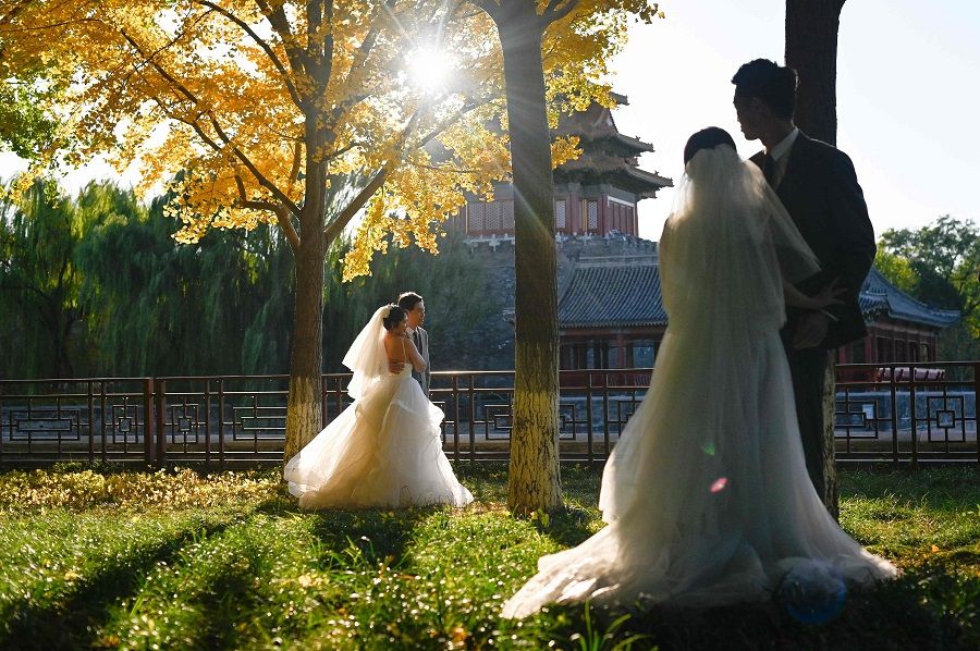 Two couples prepare to pose for their wedding pictures outside the Forbidden City in Beijing, China, on 31 October 2022. (Wang Zhao/AFP)