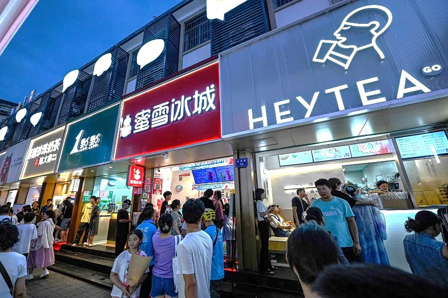 This photo taken on 15 August 2024 shows people walking past bubble tea shops at a night market in Hangzhou, Zhejiang province, China.