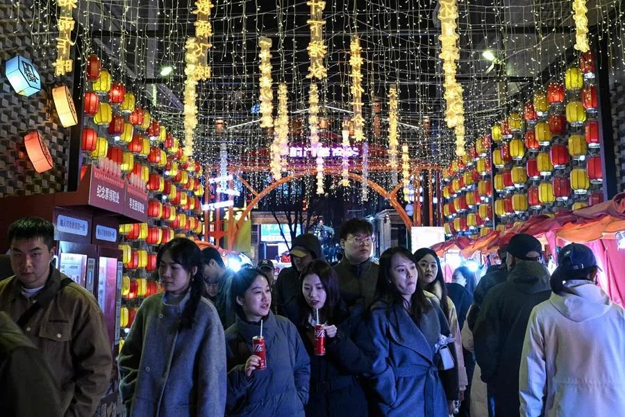 People walk at a shopping area in Beijing on 17 March 2026. (Adek Berry/AFP)