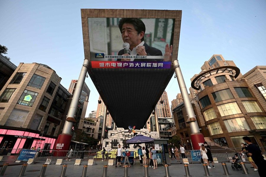 A large video screen shows a news broadcast featuring an image of former Japanese Prime Minister Shinzo Abe in Beijing on 8 July 2022. (Noel Celis/AFP)