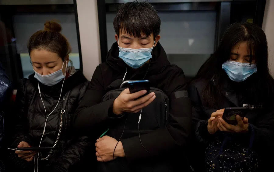 People wearing face masks use their mobile phone on a subway in Beijing on 19 December 2020. (Noel Celis/AFP)