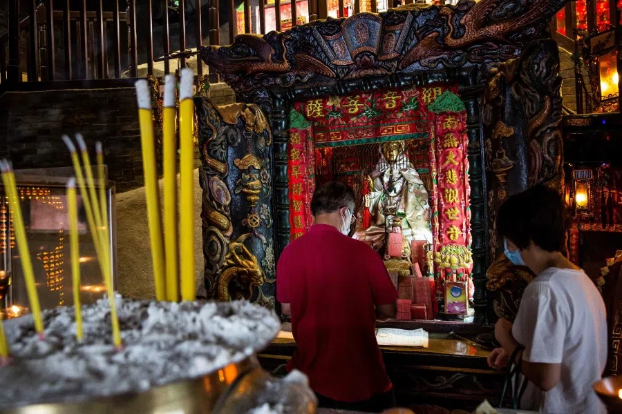 People walk through a temple in the Tai Hang district of Hong Kong on 17 September 2021. (Isaac Lawrence/AFP)