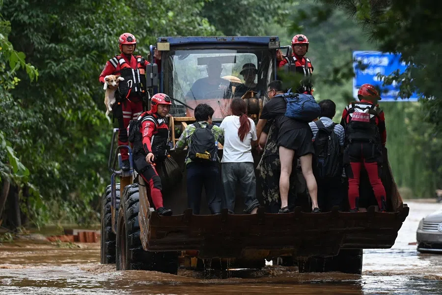 Rescue team members evacuate residents from their home on a flooded road after heavy rains at Taishitun village in Miyun district, on the outskirts of Beijing on 28 July 2025. (Jade Gao/AFP)