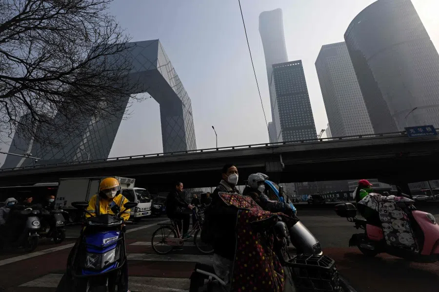 People wait for traffic lights on a street at the central business district in Beijing on 5 March 2023 (Jade Gao/AFP)