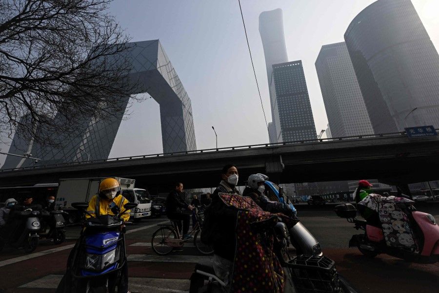People wait for traffic lights on a street at the central business district in Beijing on 5 March 2023 (Jade Gao/AFP)