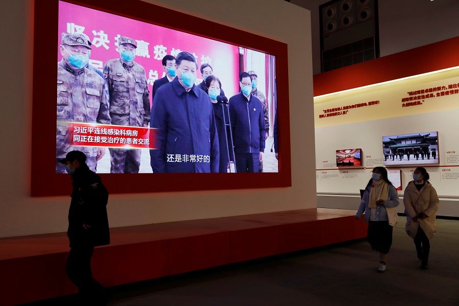 Visitors walk near a screen showing Chinese President Xi Jinping during an exhibition on the fight against the Covid-19 outbreak, at Wuhan Parlor Convention Center that previously served as a makeshift hospital for Covid-19 patients in Wuhan, Hubei province, China, 31 December 2020. (Tingshu Wang/Reuters)