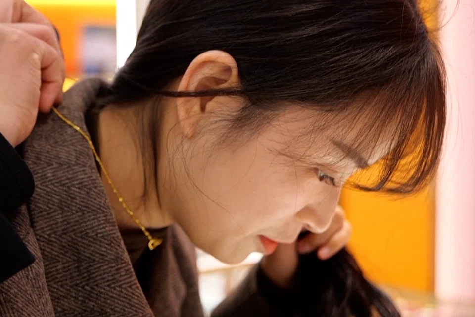 A customer tries on gold jewelry in Huzhou, Zhejiang Province, China. (Screen grab from CCTV)
