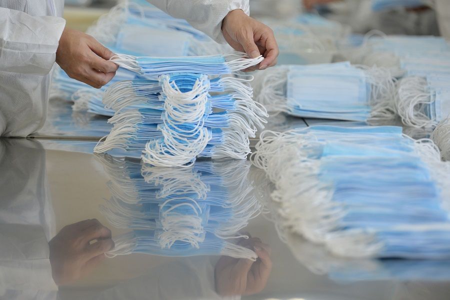 This photo taken on 18 February 2020 shows a worker sorting face masks being produced to satisfy increased demand during the Covid-19 pandemic, at a factory in Nanjing, China. (STR/AFP)
