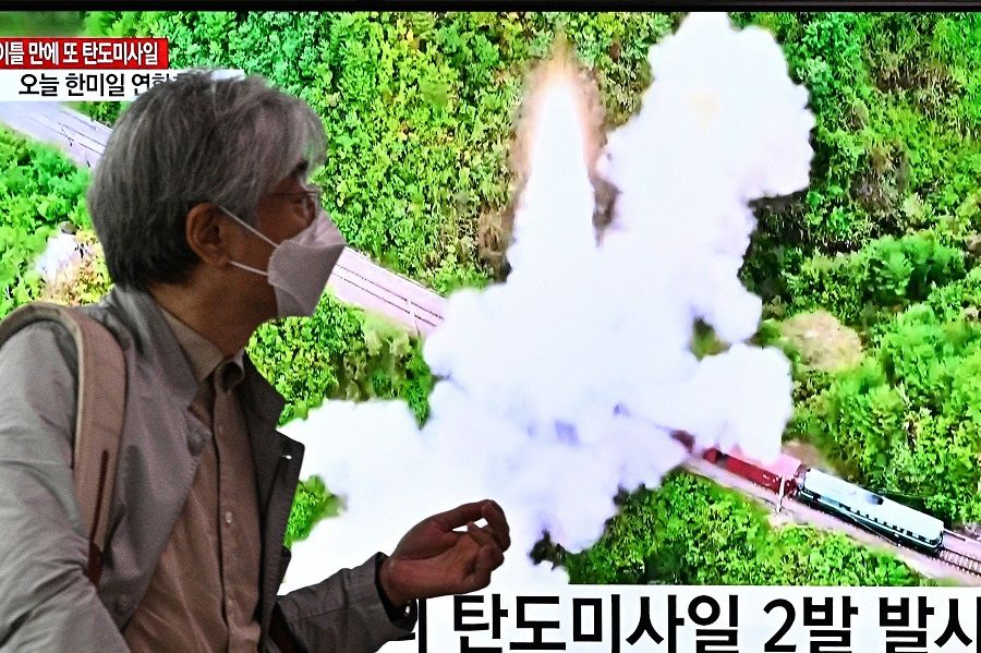 A man walks past a television report showing a news broadcast with file footage of a North Korean missile test, at a railway station in Seoul, South Korea, on 6 October 2022. (Anthony Wallace/AFP)