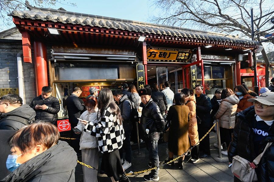 People queue to enter a restaurant in the Dongcheng district of Beijing on 3 December 2023. (Pedro Pardo/AFP)