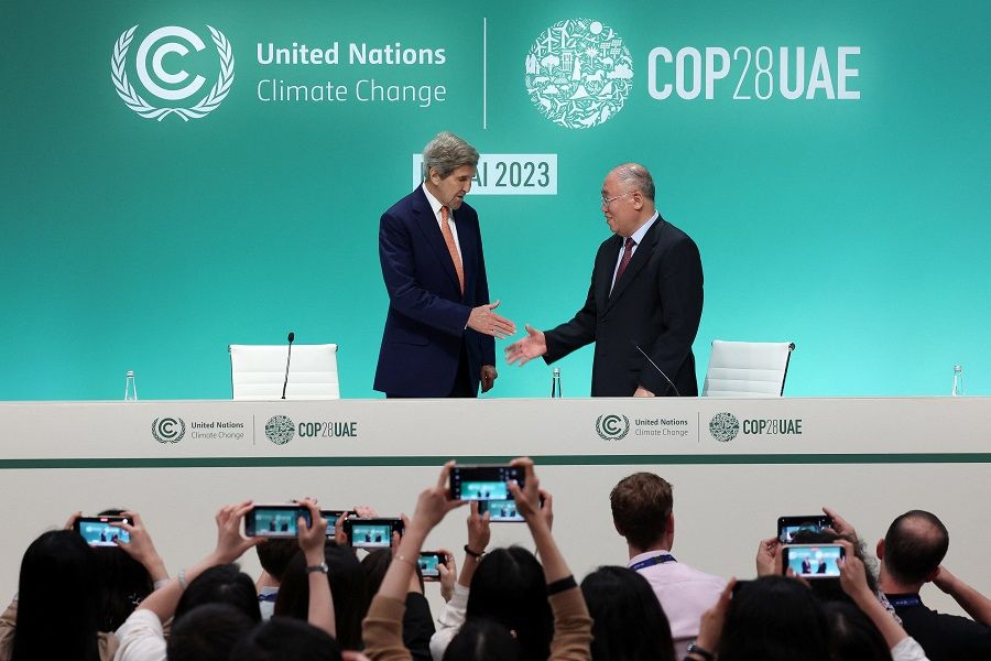 US Climate Envoy John Kerry and Chinese Climate Envoy Xie Zhenhua reach to shake hands at a press conference, after a draft of a negotiation deal was released, at COP28 in Dubai, United Arab Emirates, on 13 December 2023. (Amr Alfiky/Reuters)