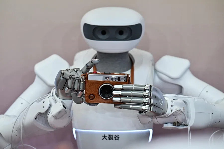 A humanoid robot prepares to take a picture with a Instax camera during the World Artificial Intelligence Conference (WAIC) in Shanghai on 18 July 2026.