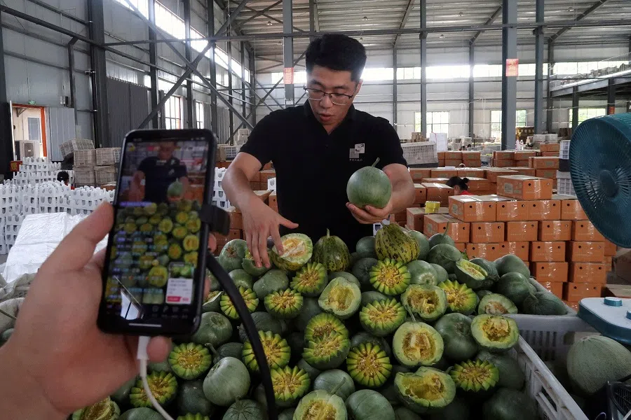 Livestreamers in a fruit-packing warehouse sell melons online during an organised tour to Zhengde (Shandong) Supply Chain Company Limited in Weifang, Shandong province, China, on 9 June 2024. (Mei Mei Chu/Reuters)