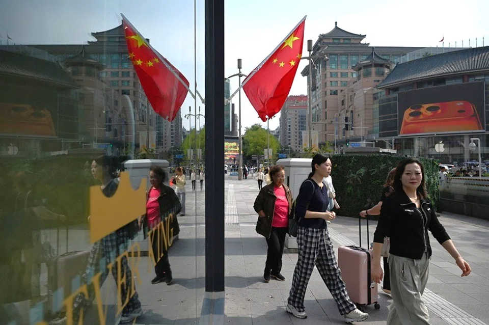 People walk outside a shopping mall in Beijing on 7 October 2025. (Greg Baker/AFP)