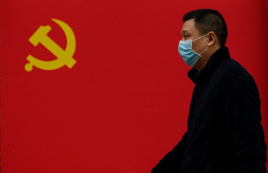 A man walks past a Communist Party flag along a street in Wuhan, March 31, 2020. (Noel Celis/AFP)