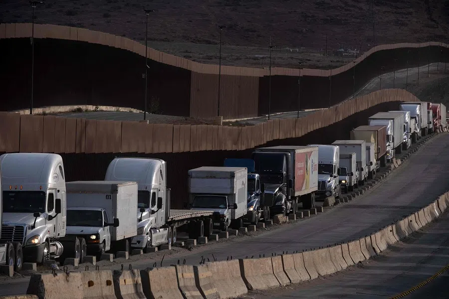 Trucks queue next to the border wall before crossing to the United States at Otay commercial port in Tijuana, Baja California state, Mexico, on 22 January 2025. (Guillermo Arias/AFP)