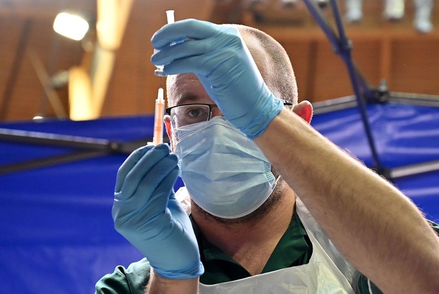 A member of the clinical staff prepares a dose of the coronavirus vaccine, at a Covid-19 vaccination centre set up inside the Bournemouth International Centre in Bournemouth, England, on 18 January 2021. (Glyn Kirk/AFP)