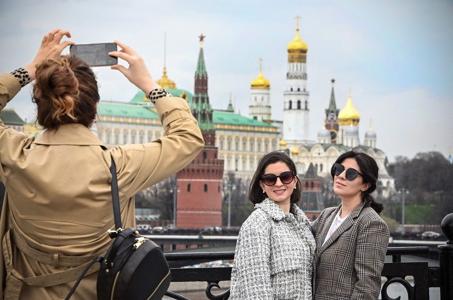 People make a selfie photo on a bridge across the Moskva River with the Kremlin in the background on 27 April 2022 in Moscow, Russia. (Alexander Nemenov/AFP)