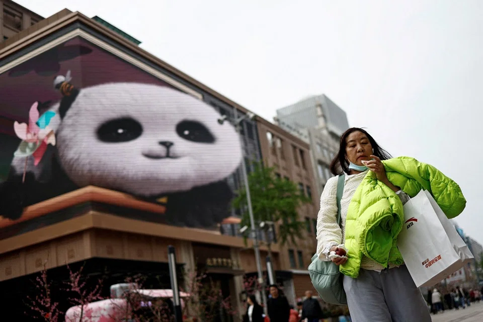 A woman walks at a shopping street in Beijing, China, on 10 April 2024. (Tingshu Wang/Reuters)