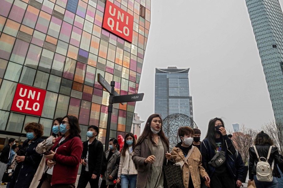 People walk past a Uniqlo store in Beijing on 5 April 2021. (Nicolas Asfouri/AFP)