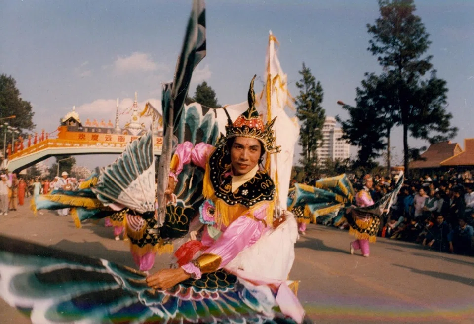 A young Dai man from Yunnan performing the Peacock Dance on the street, 1988.