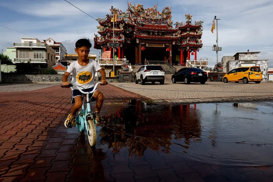 A child rides a bicycle through a puddle caused by rain in front of a temple in Penghu, Taiwan, on 8 June 2026.