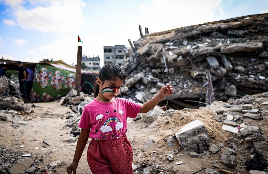 A Palestinian girl plays amidst the rubble of buildings destroyed by last month's Israeli bombardment of the Gaza Strip, in Beit Lahia, in the northern part of the Palestinian enclave on 19 June 2021. (Mahmud Hams/AFP)