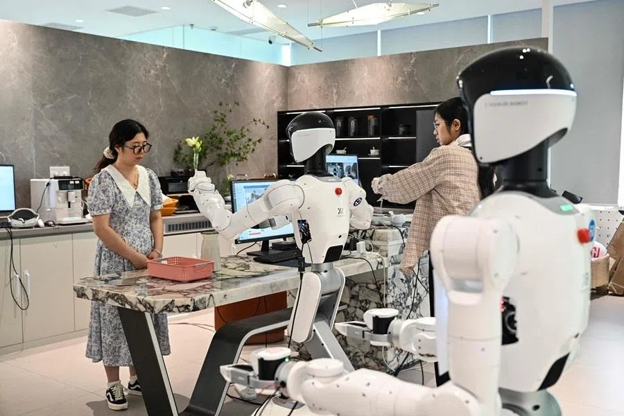 An engineer trains a humanoid robot to do household tasks at the X Square Robot facilities in Shenzhen, southern China's Guangdong province on May 22, 2026. China's robots have wowed audiences with fluid dancing and set-piece martial arts displays onstage, but their application and performance in real-life settings remains limited. For companies like X Square, the logic of launching an imperfect service lies in data collection for so-called embodied artificial intelligence. (Photo by Hector RETAMAL / AFP) / To go with AFP story China-tech-labour-lifestyle-AI, FOCUS by Emily WANG