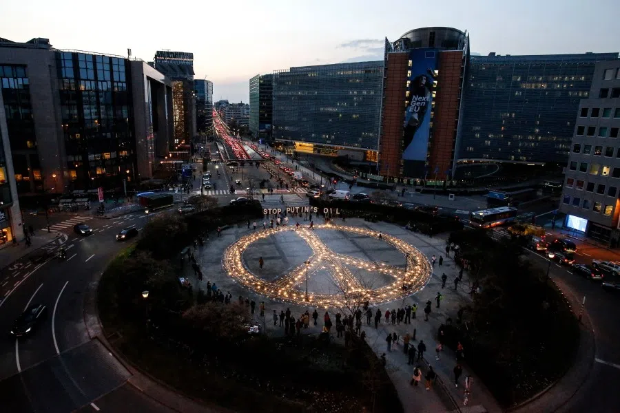 Avaaz members, demonstrators and Ukrainian activists stand around a peace sign during a vigil for Ukraine near the European Union headquarters in Brussels, on 22 March 2022. (Valeria Mongelli/AFP)