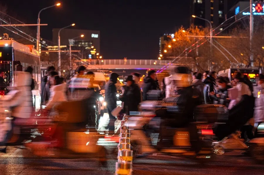 Pedestrians cross a road at night in Beijing, China, on 30 December 2024. (Na Bian/Bloomberg)