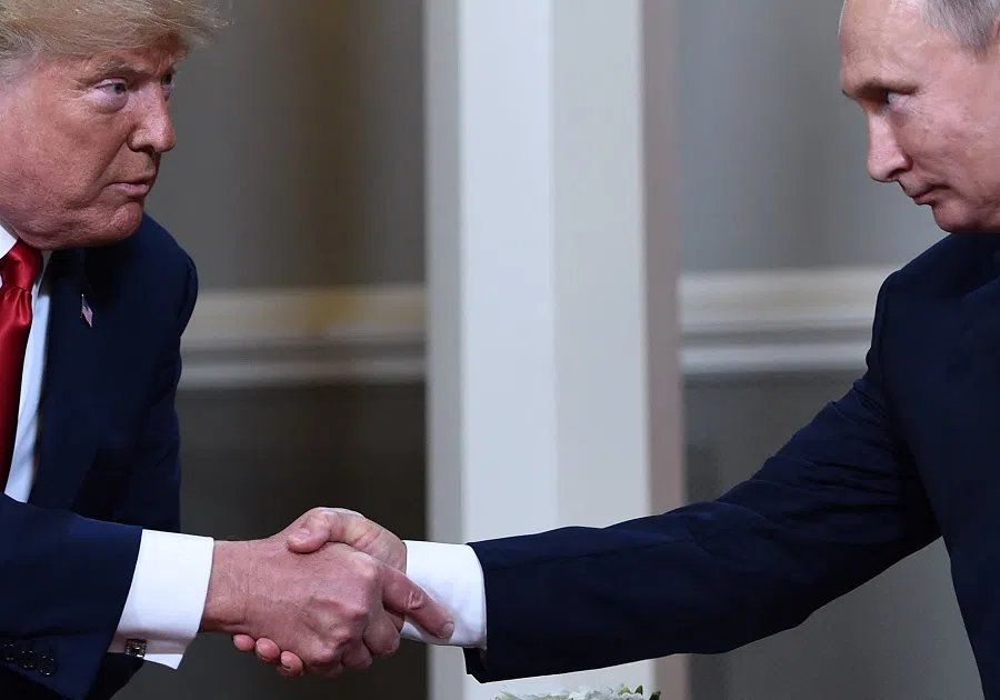 In this file photo taken on 16 July 2018, US President Donald Trump and Russian President Vladimir Putin shake hands ahead a meeting in Helsinki, Finland. (Brendan Smialowski/AFP)