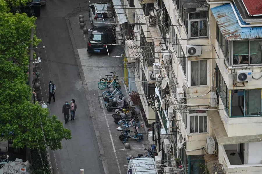 Residents walk on a street next to their neighbourhood during a Covid-19 lockdown in the Jing'an district in Shanghai on 17 May 2022. (Hector Retamal/AFP)